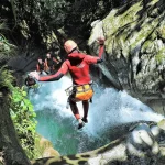 Adventurers navigating the intense waterfalls and rocky passages of Cashaurco canyon during a premium canyoning in baños ecuador tour.