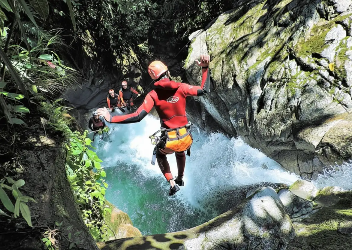 Adventurers navigating the intense waterfalls and rocky passages of Cashaurco canyon during a premium canyoning in baños ecuador tour.
